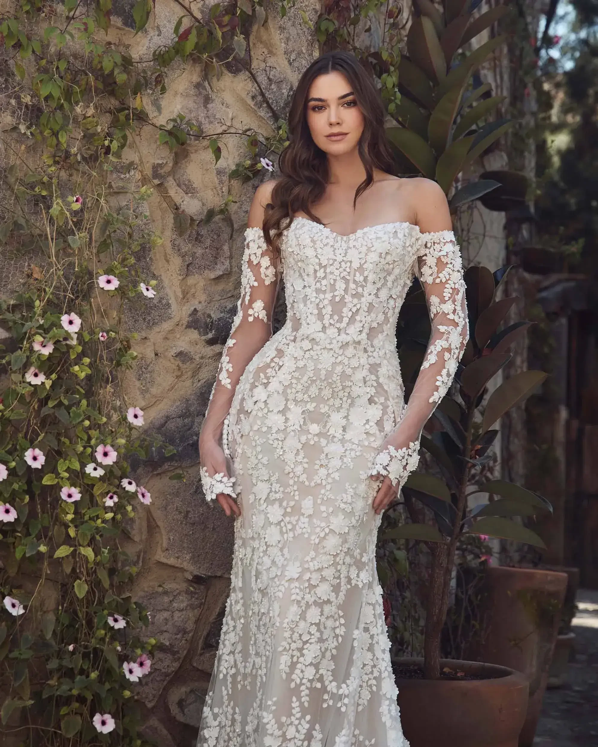 model is wearing a lace strapless fit and flare wedding dress with detachable optional long sleeves