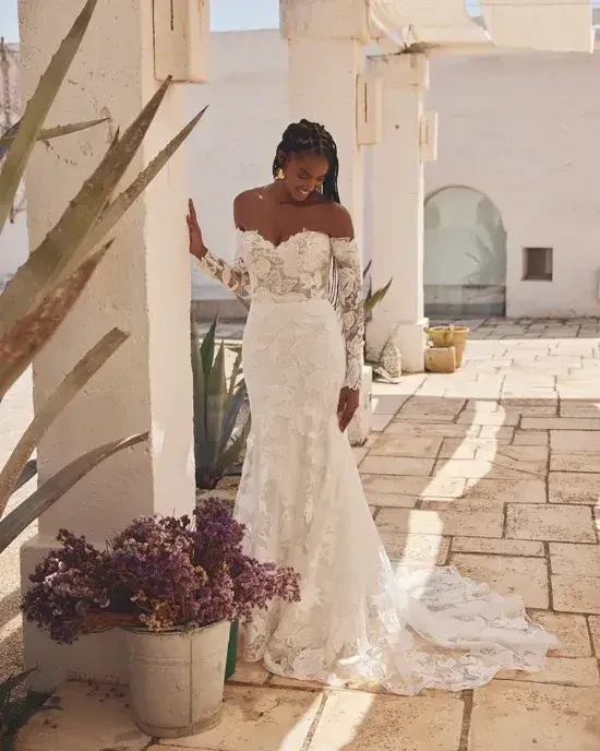model is wearing an off the shoulder lace wedding dress
